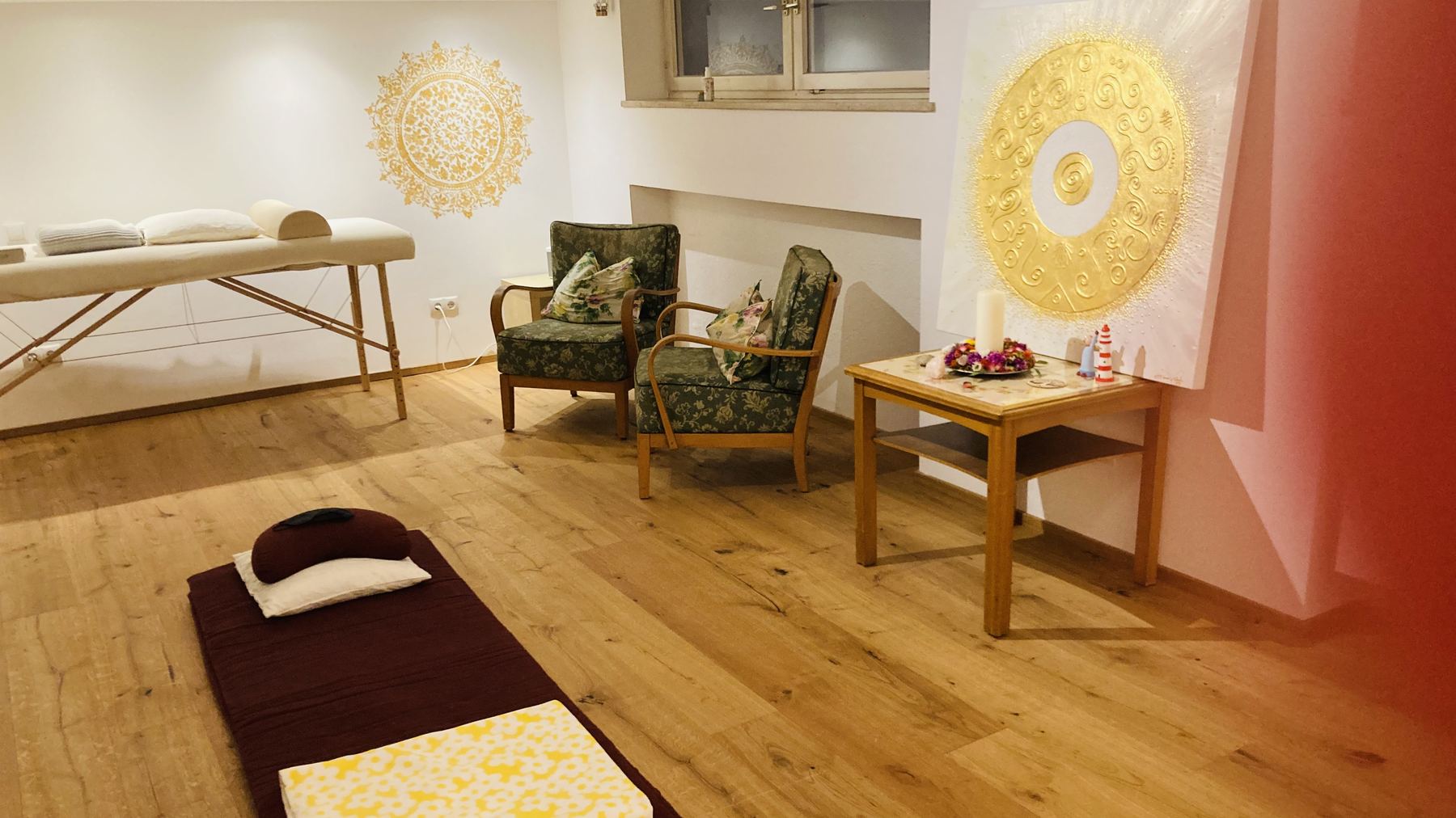 Praxisraum mit Massageliege und goldenem Mandala